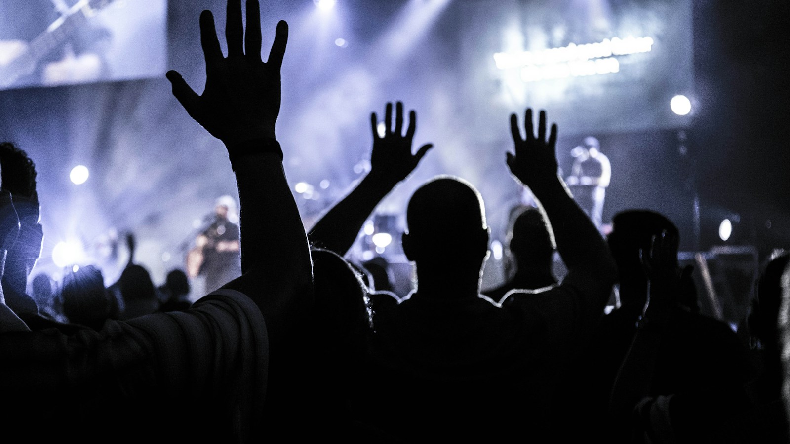 Silhouette of a worship crowd at a concert singing the Israel Houghton classic